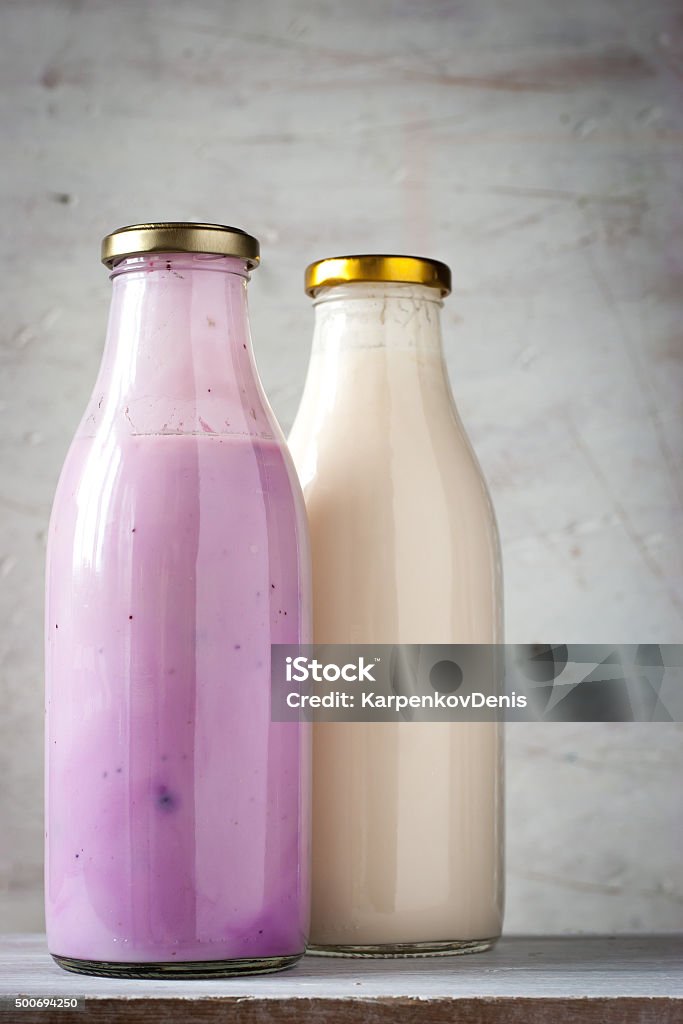 Natural and fruit yogurt in the glass bottle vertical Natural  and fruit yogurt in the glass bottle on the white wooden table vertical Appetizer Stock Photo
