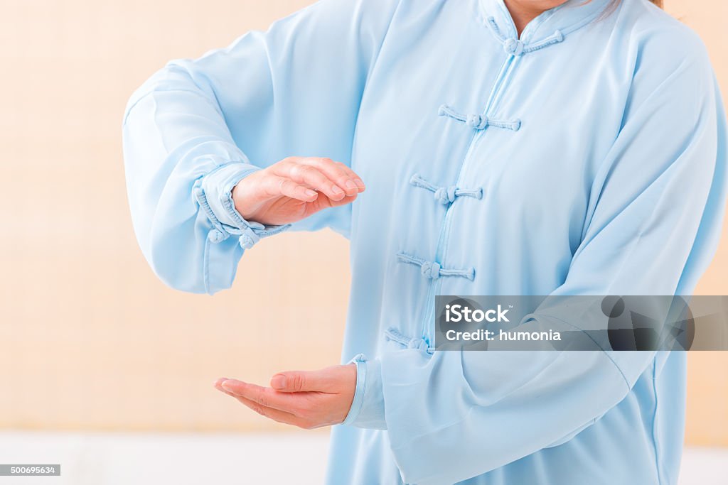 Woman doing qi gong tai chi exercise Beautiful woman doing qi gong tai chi exercise wearing professional, original Chinese clothes at gym Active Lifestyle Stock Photo