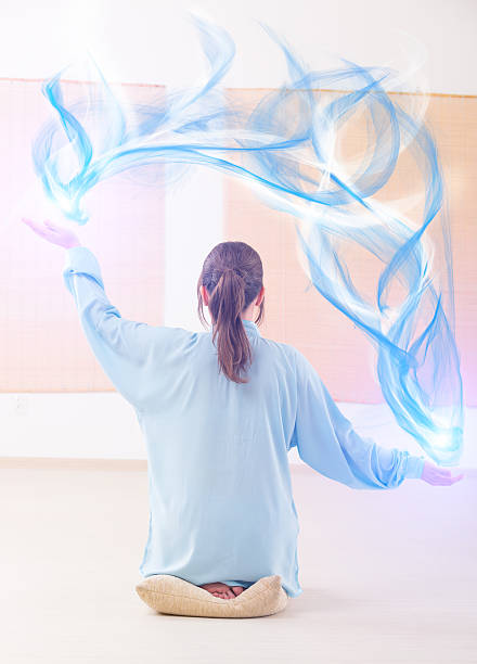 Beautiful woman doing qi gong tai chi exercise or reiki wearing professional, original Chinese clothes at gym