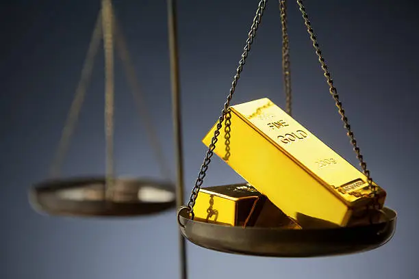 Gold ingots on brass scale  on dark background