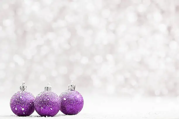 Photo of Christmas ball in the snow on blurred light background.