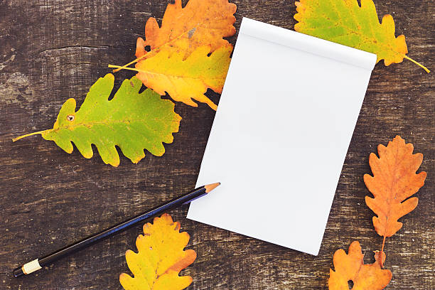 istock paper with pencil surrounded by colorful autumn leaves 500700826