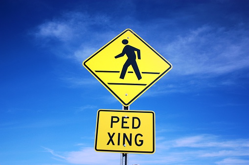 A yellow pedestrian access sign on a pole