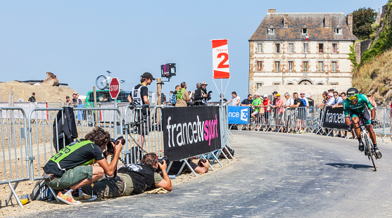 Mont Saint Michel, France- July 10, 2013: Photographers shoot from the roadside a cyclist in action during the stage 11 of the edition 100 of Le Tour de France 2013, a time trial between Avranches and Mont Saint Michel.