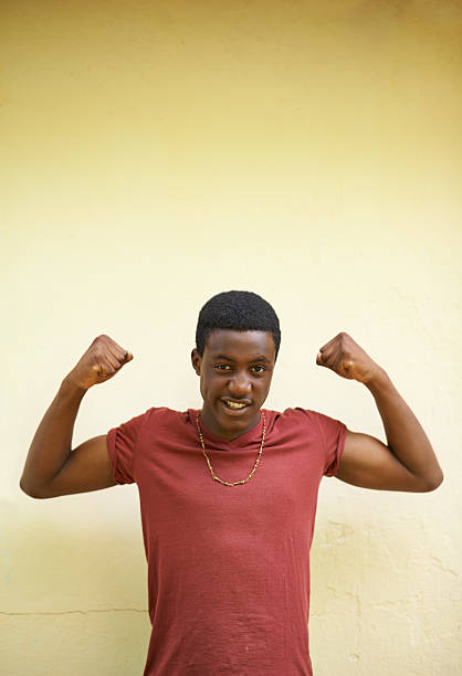 Shot of a teenage boy showing off his muscles while standing against a wallhttp://195.154.178.81/DATA/i_collage/pi/shoots/783557.jpg