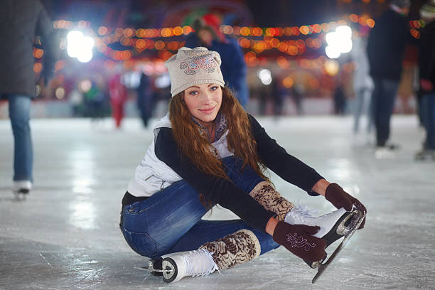 Close-up of ice rink surface with visible skate marks and scratches. Person standing on ice wearing figure skates. Winter sport background with copy space.