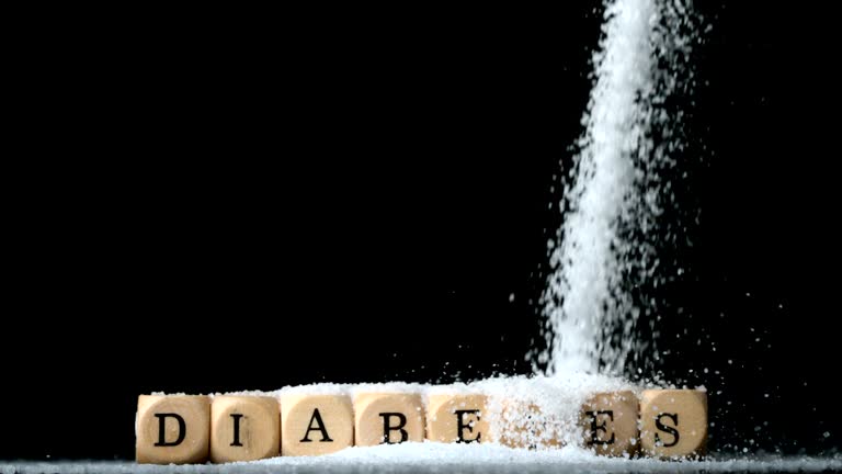 Sugar powder being poured over dice spelling out diabetes