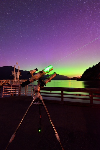 telescope with laser beam under aurora borealis at Porteau Cove Provincial Park