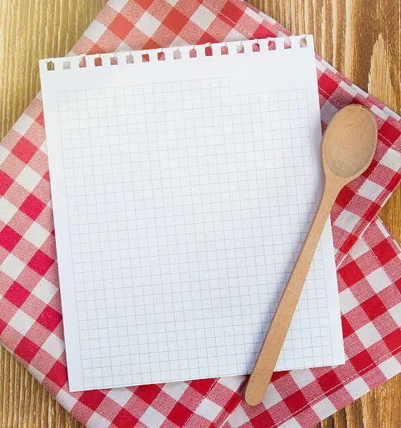 Recipe white page on picnic cloth on wooden background.Paper with copyspace for kitchen notes.Clean blank.