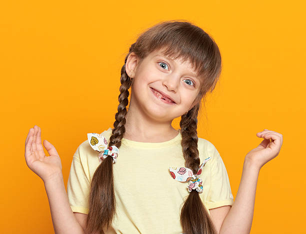 istock lost tooth girl portrait, studio shoot on yellow background 500726372