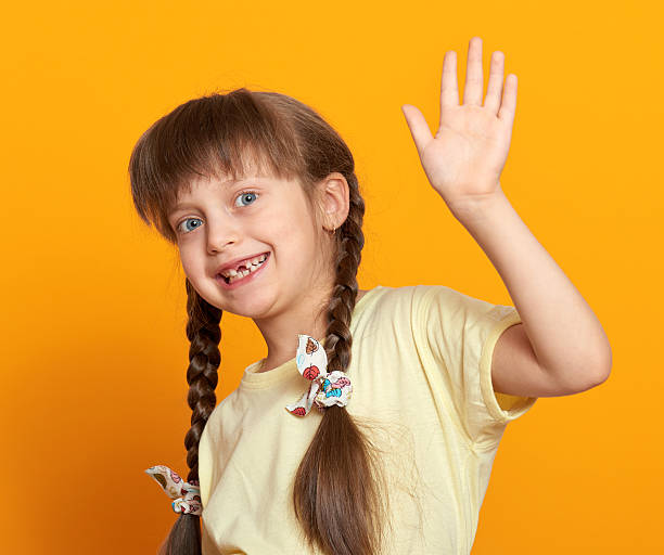 istock lost tooth girl portrait, studio shoot on yellow background 500726458