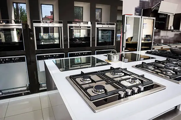 Rows of gas stoves with stainless tray selling in appliance retail store