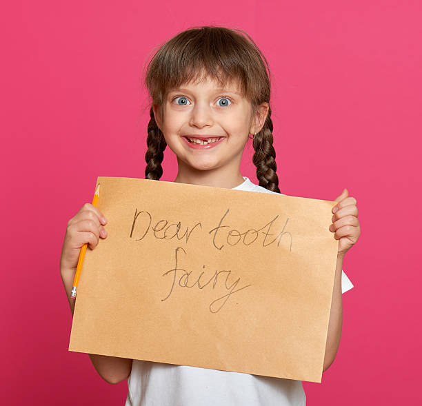 istock lost tooth girl portrait, studio shoot on pink background 500728422