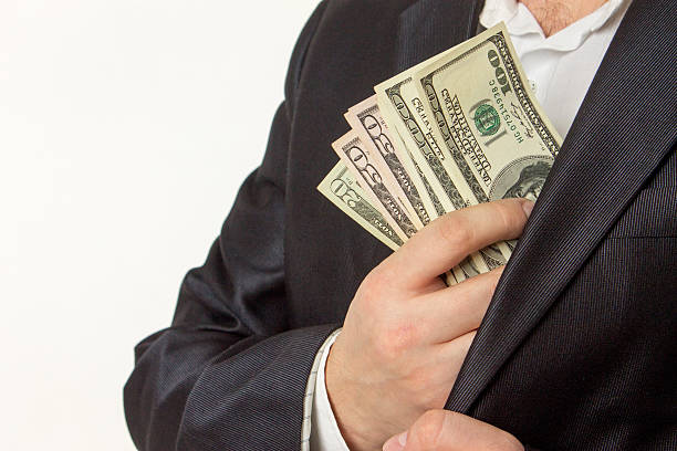 Businessman putting money in suit jacket pocket Businessman putting money in suit jacket pocket. leather pocket clothing hide stock pictures, royalty-free photos & images