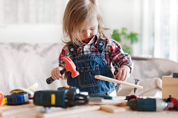 Little Girl Power Litte 2 years old girl who dreams of becoming a carpenter girl with a hammer stock pictures, royalty-free photos & images