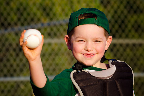 Young child in catcher's gear throwing baseball stock photo