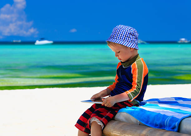 istock little boy playin on touch pad at the beach 500736387
