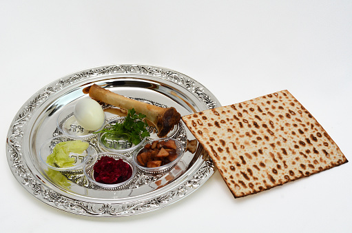 Matzo bread next to Passover Seder Plate with The seventh symbolic item used during the seder meal on passover Jewish holiday. White background with copy space