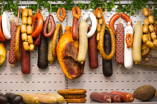 Colorful salami and deli meats hang from a rack.