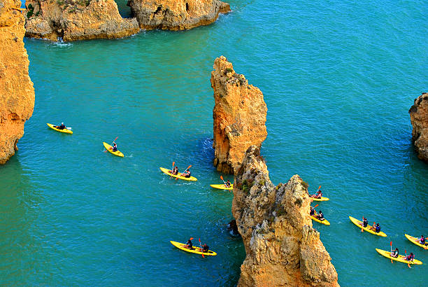 les touristes du kayak à travers la spectaculaire sur les formations rocheuses - kayaking kayak sea coastline photos et images de collection