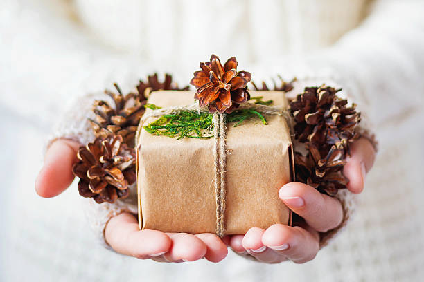 istock Woman in knitted sweater holding a present with pinecones 500747848