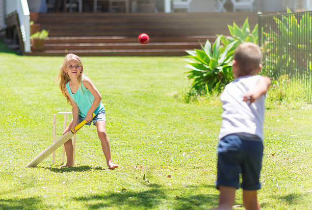 Australian kids playing cricket Color image of Australian brother and sister at their elementary age playing cricket at the backyard of their house. batting sports activity stock pictures, royalty-free photos & images