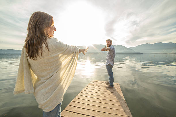 istock Couple on jetty, pulls out hands to reach each other 500748568