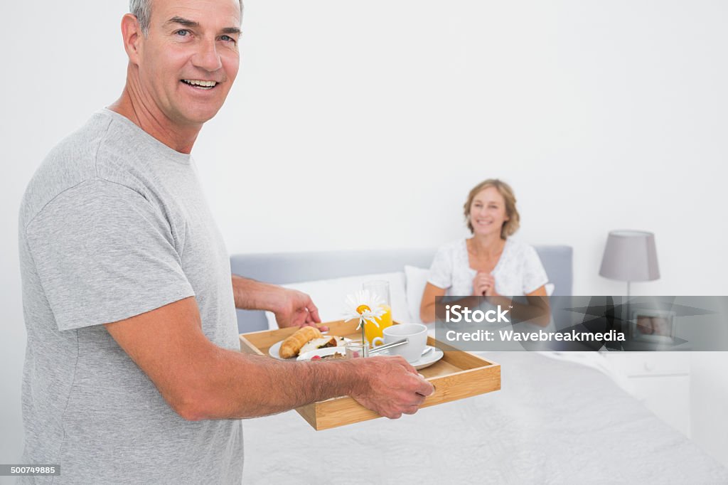 Feliz marido ofrecen desayuno en la cama con el placer de esposa - Foto de stock de 40-49 años libre de derechos