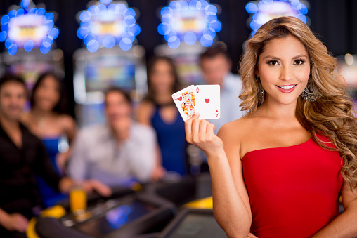Woman at the casino holding cards and smiling  (Note: Card design is our own)
