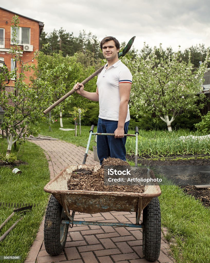 smiling man with spade and garden wheelbarrow Portrait of smiling man with spade and garden wheelbarrow Activity Stock Photo