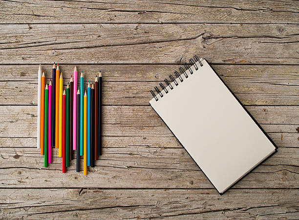 istock Colorful pencil crayons and notebook on wooden background 500754482