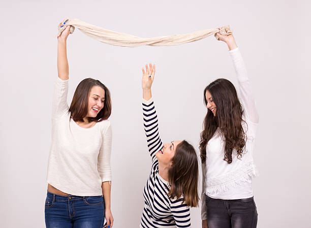 short girl trying to reach taller girls scarf short girl trying to reach taller girls scarf tall person stock pictures, royalty-free photos & images