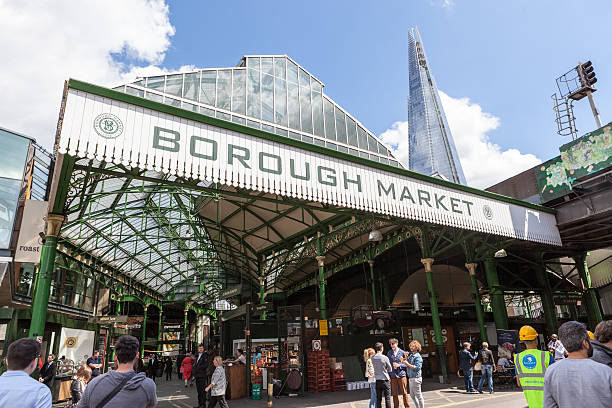 Entrance to Borough Market in London London, UK - 14 May 2014: Shoppers and workers milling around outside the entrance to Borough Market, near London Bridge. This popular market has many stalls selling different types of food from over the world. borough market stock pictures, royalty-free photos & images