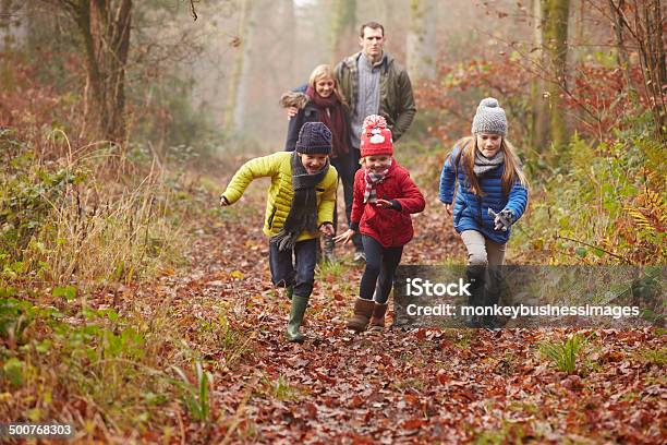 Familia Caminando A Través De Un Bosque De Invierno Foto de stock y más banco de imágenes de Familia