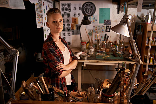 Organized chaos Shot of a beautiful young woman sitting in a workshop carpenter portrait stock pictures, royalty-free photos & images