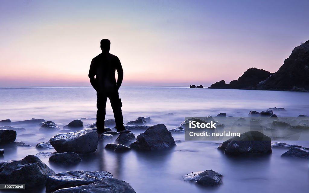 Homem de pé apenas na praia durante o nascer do sol - Foto de stock de Adulto royalty-free