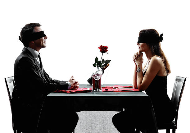 blindfolded woman sitting at a table - SuperStock