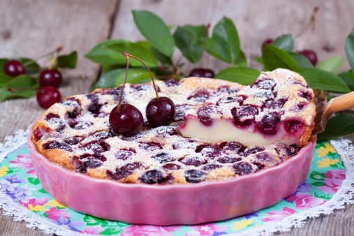 Slice of clafoutis with cherry in ceramic form