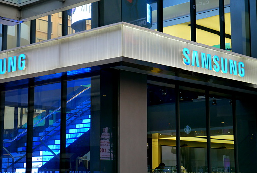 Bangkok, Thailand – December 10, 2015: Exterior view of a Samsung shop in the Siam Square area of Bangkok, Thailand. People walk around the area. The picture is taken from the walkway of sky train station.