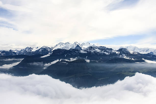 Sarnersee (lake) beneath fog lingering around snowy peaks of Tannhorn Brienzer Rothorn, Arnihaaggen and Schwalmere massif.