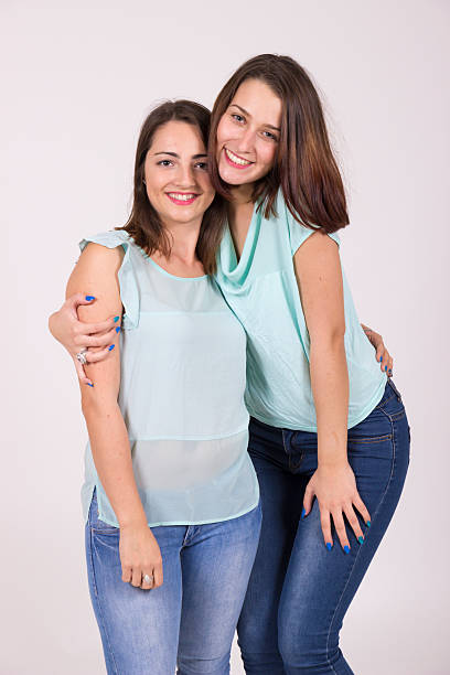 Two lookalike sisters, cute and intimate portrait in studio