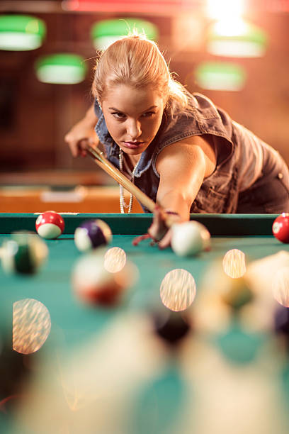 Beautiful woman playing pool game in a pool hall.