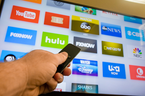 Las Vegas, USA - December 8, 2015: A young man browsing the selection of streaming TV options on the Apple TV. Apple TV is a device built by Apple Computers for streaming Television content and playing games. 