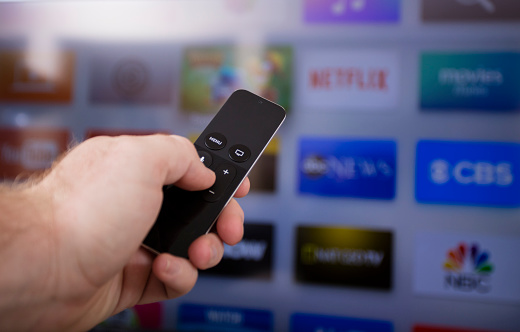 Las Vegas, USA - December 8, 2015: A young man browsing the selection of streaming TV options on the Apple TV. Apple TV is a device built by Apple Computers for streaming Television content and playing games. 