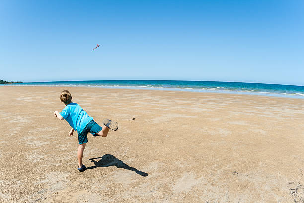 junge werfen boomerang beach - australia boomerang aboriginal aborigine stock-fotos und bilder