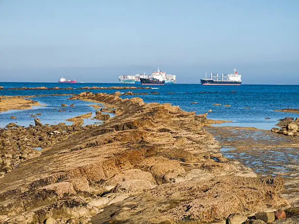 view from the rocky costline to oil tankers and container ships waiting in the bay of Algeciras, Andalusia, Spain. Entrance of the strait of Gibraltar