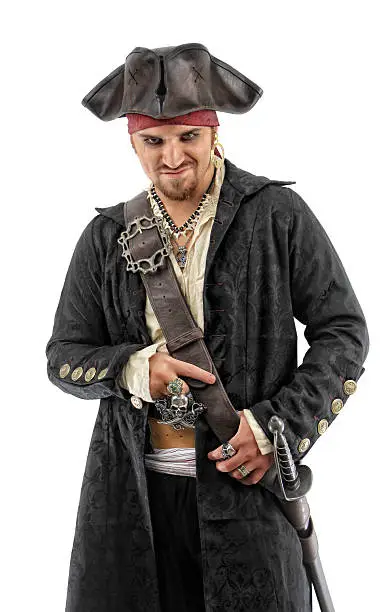 Photo of a pirate wearing an intricately detailed black coat and leather hat. He carries a sword at his side and a smugly sinister smile on his face. The subject is isolated on a white background.