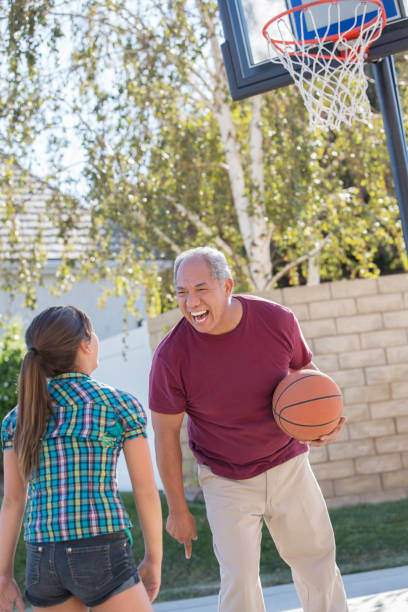 großvater und enkelin spielen basketball in der einfahrt - basketball basketball hoop california southern california stock-fotos und bilder