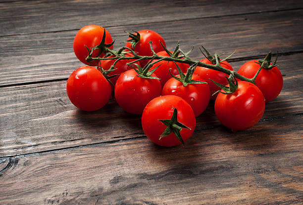 frische cherry-tomaten auf holz-hintergrund - cherry tomato fotos stock-fotos und bilder