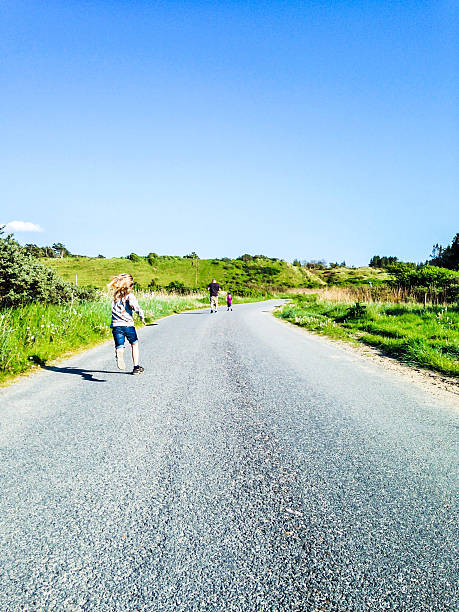rear view of man running down road with two sons, denmark - mobilestock freedom enjoyment blue стоковые фото и изображения